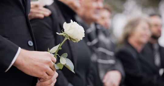 Man holding a white rose in a funeral